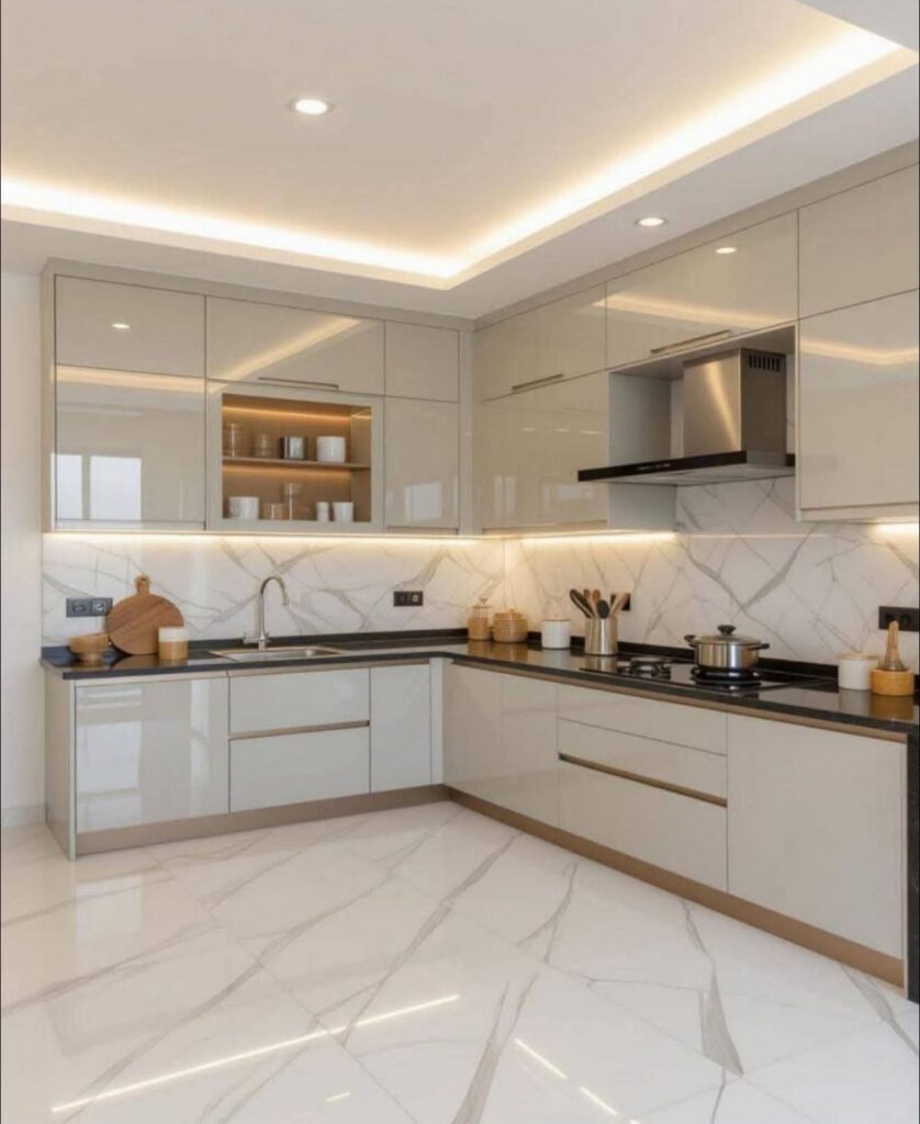 A contemporary high-gloss modular kitchen featuring a seamless marble-patterned backsplash, sleek handle-less cabinetry, and warm integrated LED cove lighting for a luxurious, airy feel.