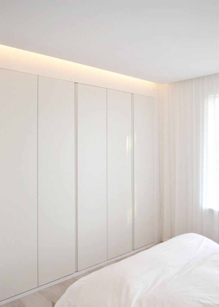 Seamless High-Gloss Floor-to-Ceiling Fitted Wardrobe with Integrated LED Cove Lighting.