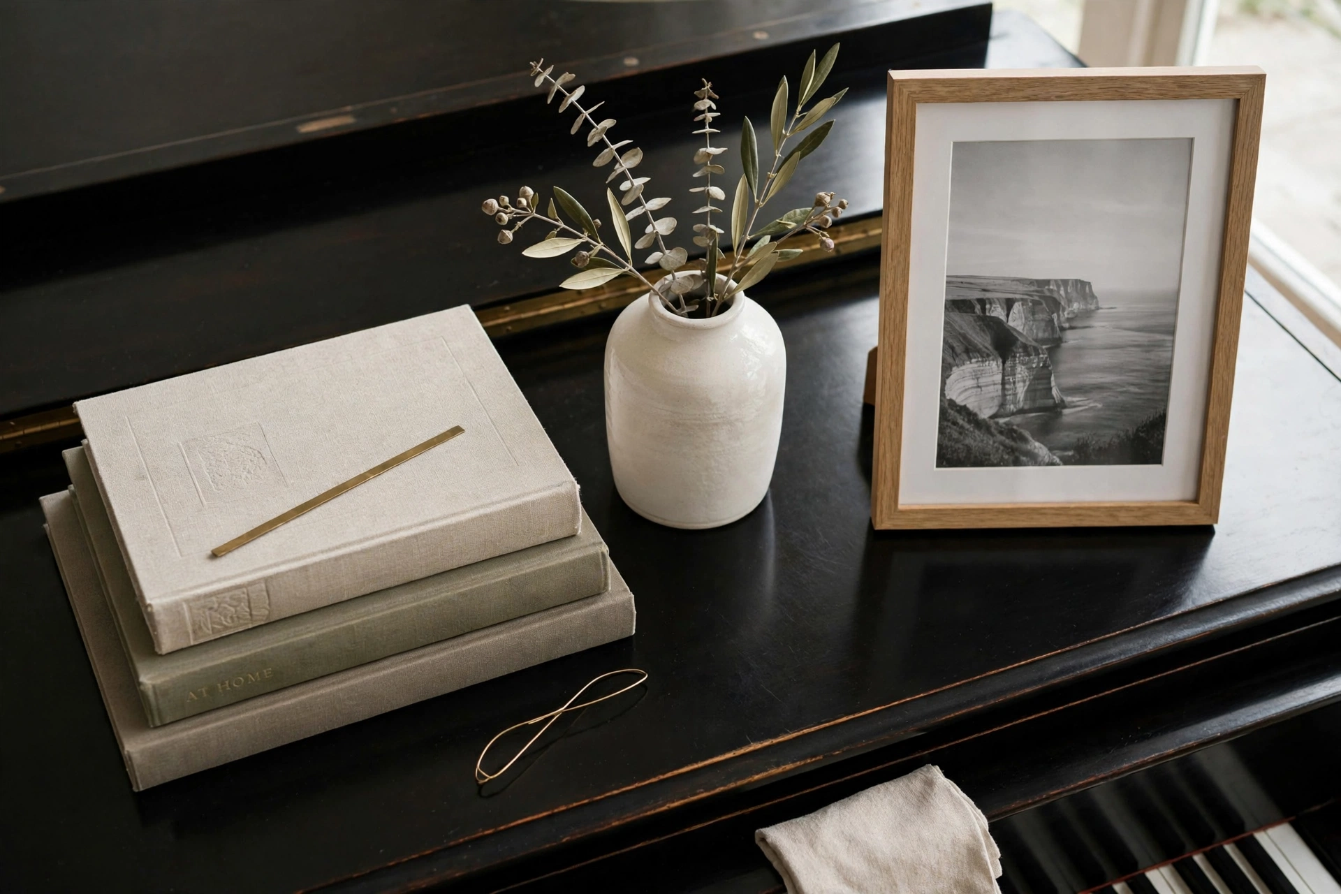 Piano top styled with books a vase and framed photo with restraint