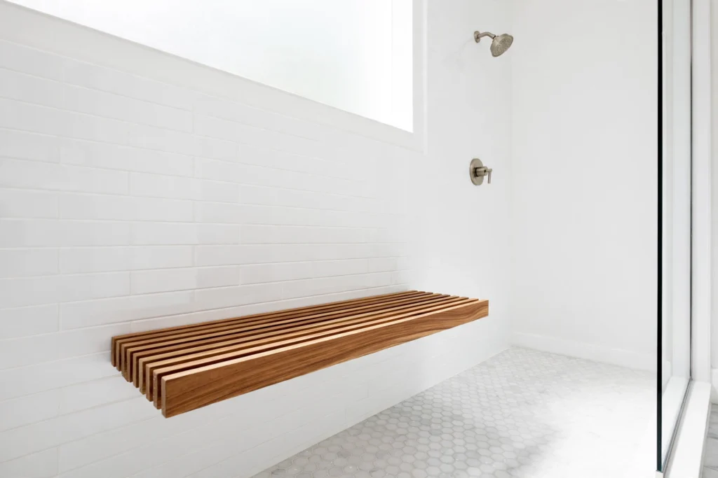 Floating teak slatted bench mounted on a white shower wall