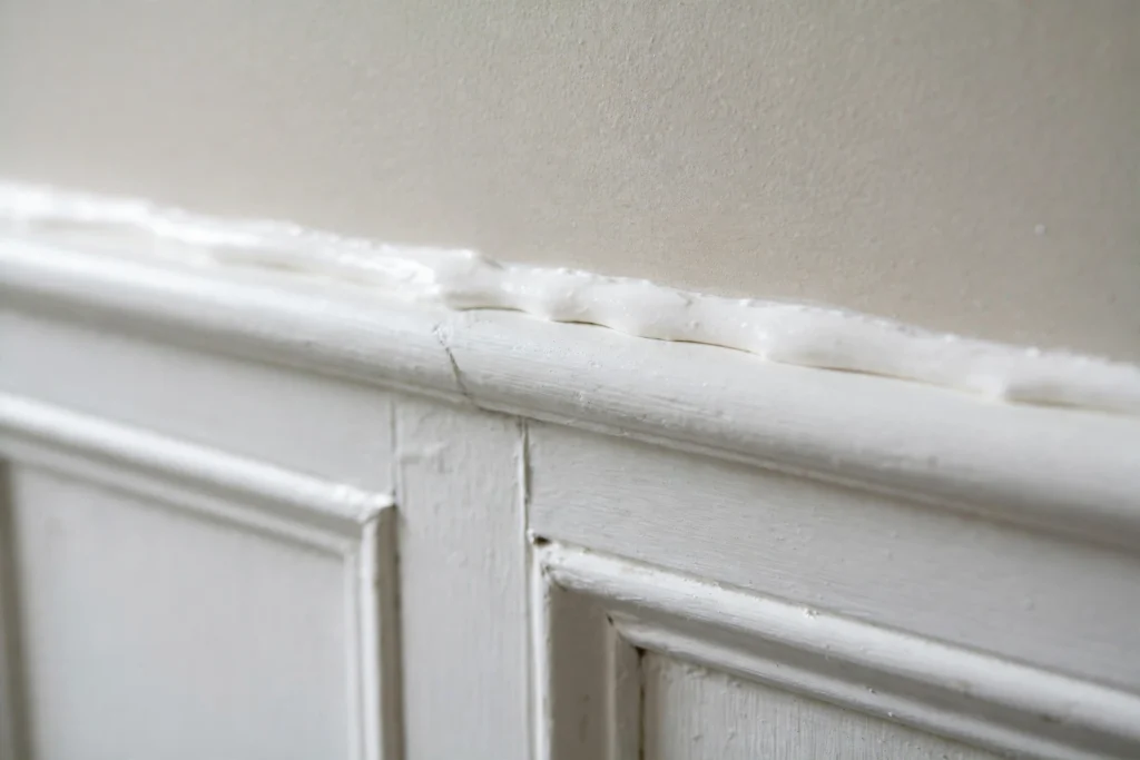 Close up of caulked seams sealing bathroom wainscoting edges