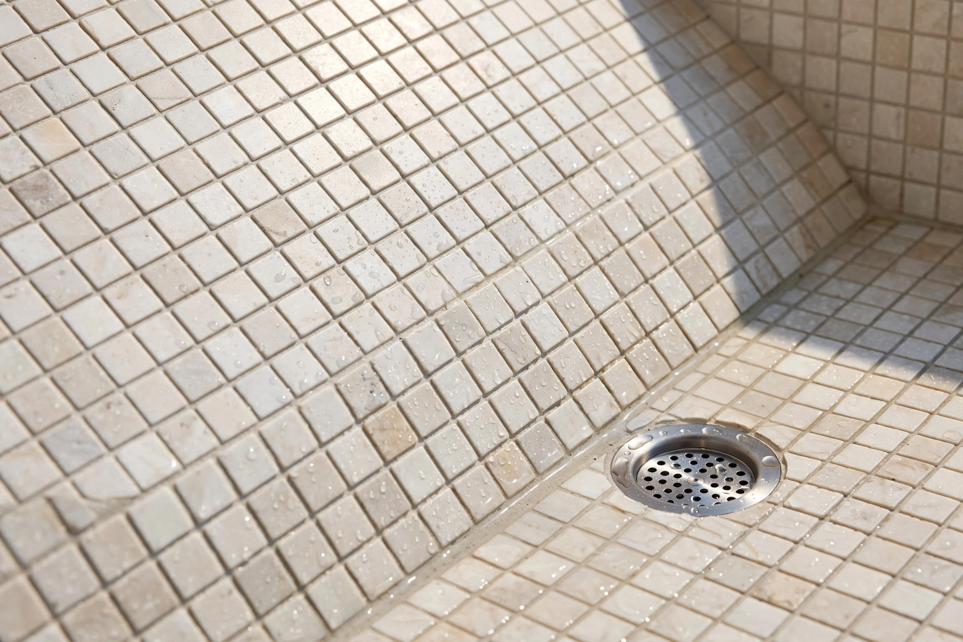 Close-up of tiled bench seat sloping toward the shower drain