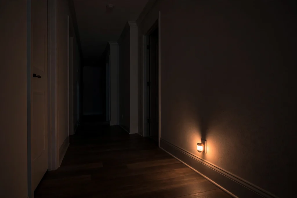 Entryway lighting ideas with a warm motion-sensor night light glowing along a hallway baseboard